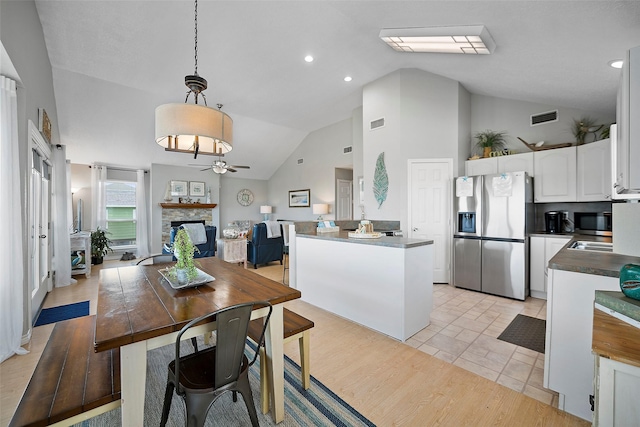 kitchen featuring appliances with stainless steel finishes, decorative light fixtures, white cabinetry, ceiling fan, and a stone fireplace