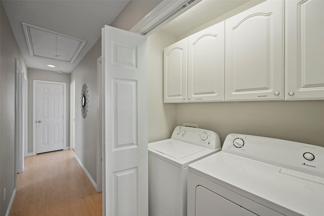 laundry room with cabinets, light wood-type flooring, and washing machine and clothes dryer