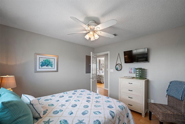 bedroom with a textured ceiling, ceiling fan, and light hardwood / wood-style flooring