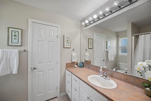 bathroom with toilet, tile patterned floors, vanity, and a textured ceiling