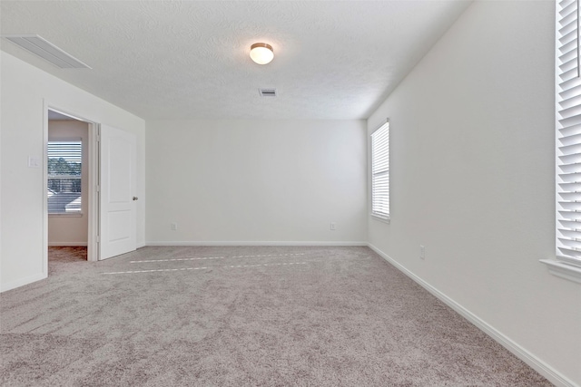 carpeted empty room with a textured ceiling