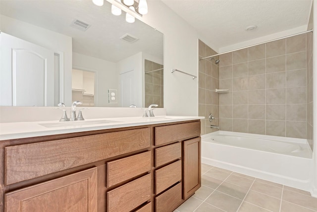 bathroom with tile patterned flooring, vanity, and tiled shower / bath