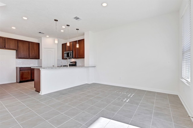 kitchen with light tile patterned floors, pendant lighting, light stone counters, and appliances with stainless steel finishes