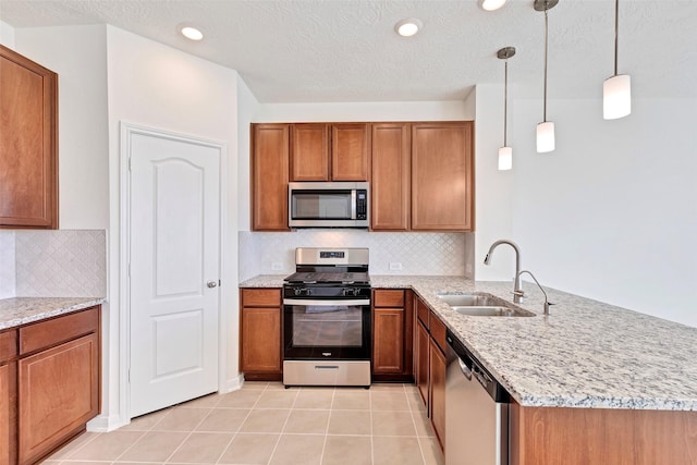 kitchen with appliances with stainless steel finishes, kitchen peninsula, sink, decorative light fixtures, and light tile patterned flooring