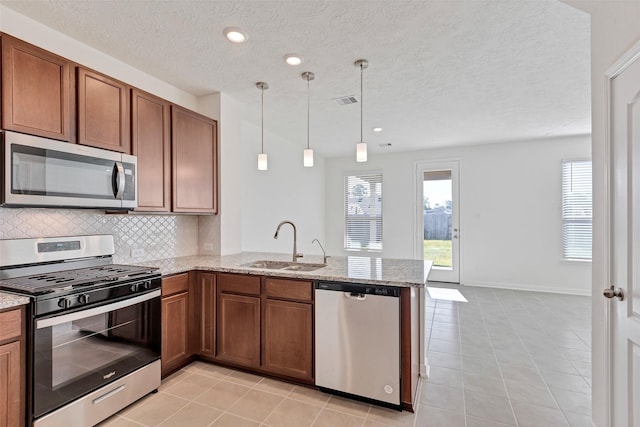 kitchen featuring appliances with stainless steel finishes, pendant lighting, sink, and kitchen peninsula