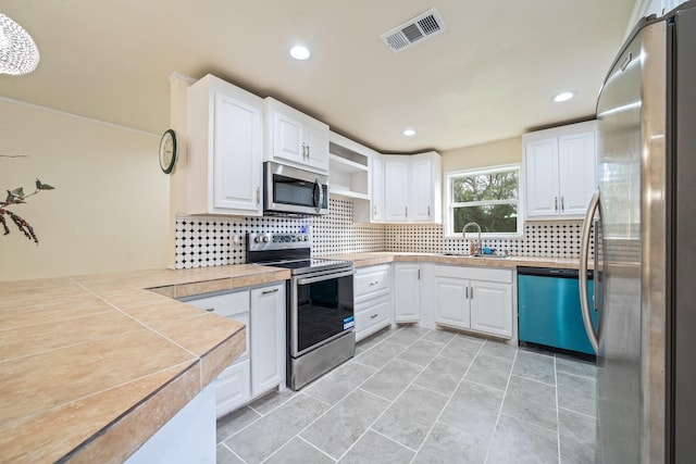 kitchen with sink, stainless steel appliances, kitchen peninsula, and white cabinetry