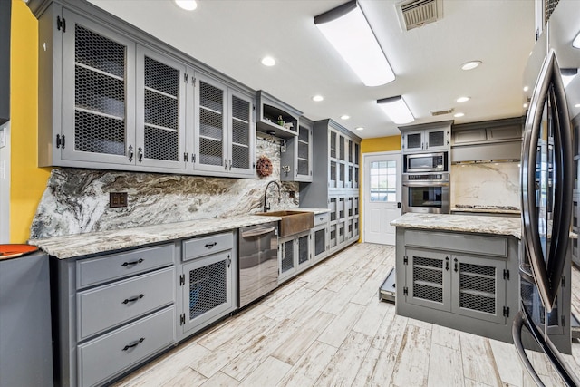 kitchen with appliances with stainless steel finishes, gray cabinets, and decorative backsplash