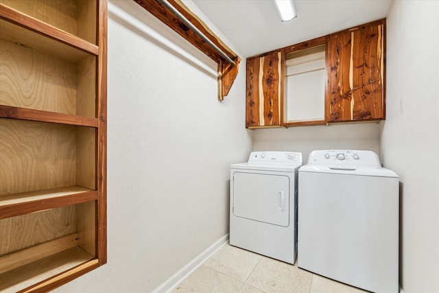 clothes washing area with light tile patterned flooring, washing machine and clothes dryer, and cabinets