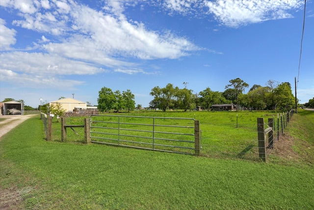 view of gate with a rural view and a lawn