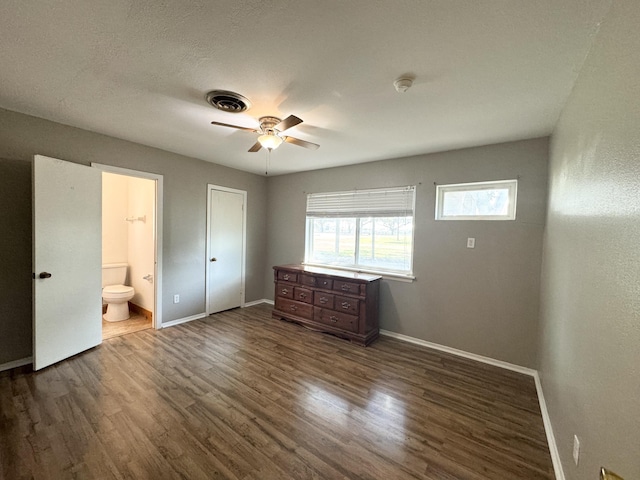 unfurnished bedroom with connected bathroom, a closet, ceiling fan, and dark wood-type flooring