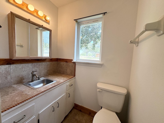 bathroom featuring toilet, vanity, tile patterned flooring, and backsplash