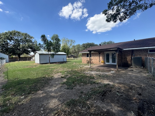 view of yard with french doors, a storage shed, and central AC unit