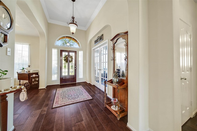 entryway with ornamental molding, a towering ceiling, dark hardwood / wood-style flooring, and french doors