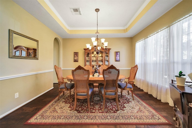 dining area with an inviting chandelier, dark hardwood / wood-style floors, and a raised ceiling