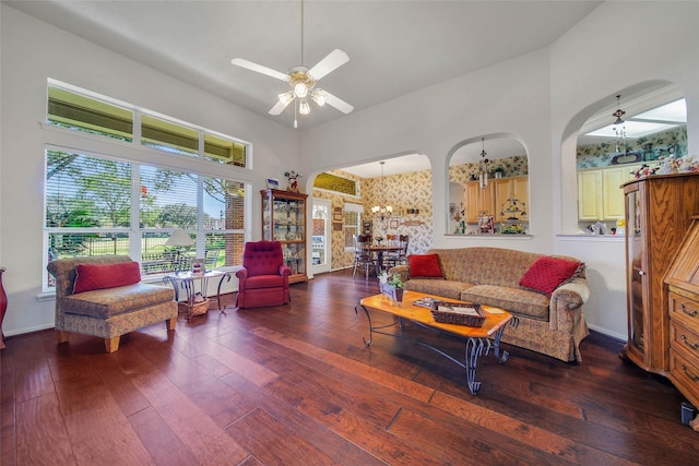 living room featuring dark hardwood / wood-style flooring, ceiling fan with notable chandelier, and a high ceiling