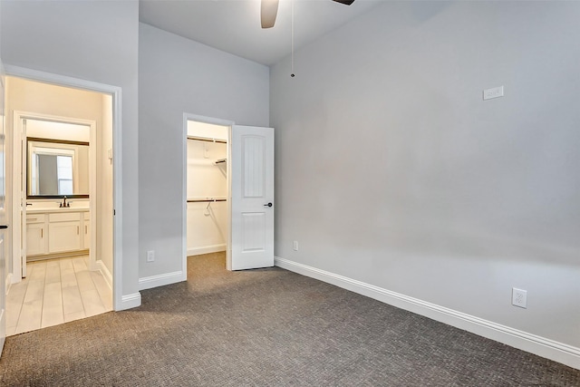 unfurnished bedroom featuring a spacious closet, a towering ceiling, ceiling fan, a closet, and carpet floors