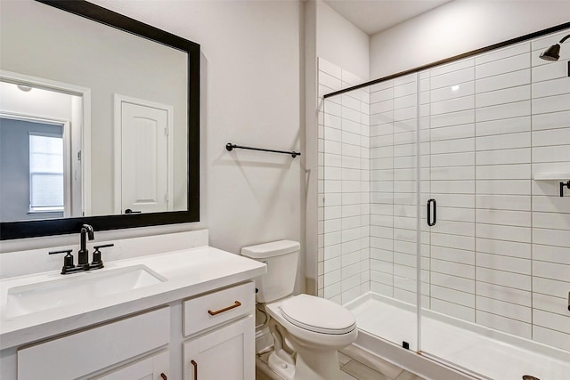 bathroom featuring toilet, vanity, and a shower with shower door