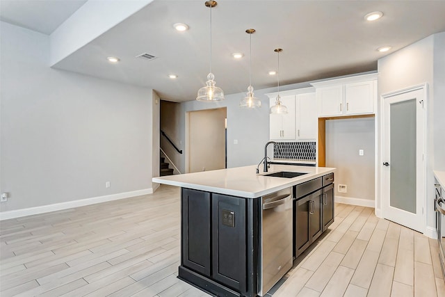 kitchen featuring sink, decorative light fixtures, white cabinetry, dishwasher, and an island with sink