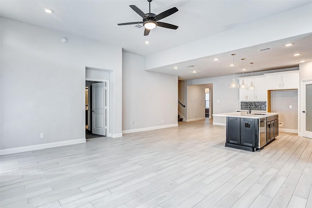 kitchen featuring decorative light fixtures, an island with sink, white cabinets, ceiling fan, and sink