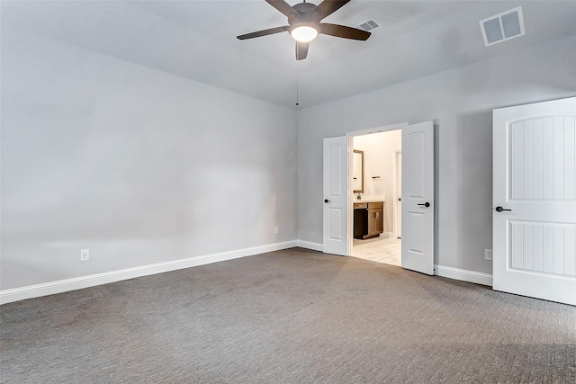 unfurnished bedroom featuring ceiling fan, light carpet, and ensuite bath