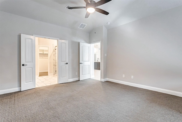 unfurnished bedroom featuring a closet, lofted ceiling, light colored carpet, a walk in closet, and ceiling fan