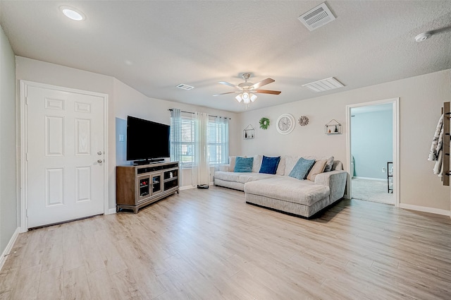 living room featuring a textured ceiling, ceiling fan, and light hardwood / wood-style floors