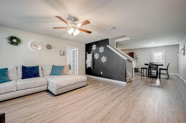 living room featuring a textured ceiling, ceiling fan, and light hardwood / wood-style floors