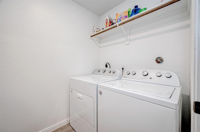 washroom with washing machine and clothes dryer and wood-type flooring