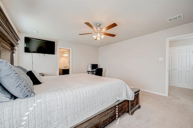 bedroom with ensuite bath, light colored carpet, and ceiling fan