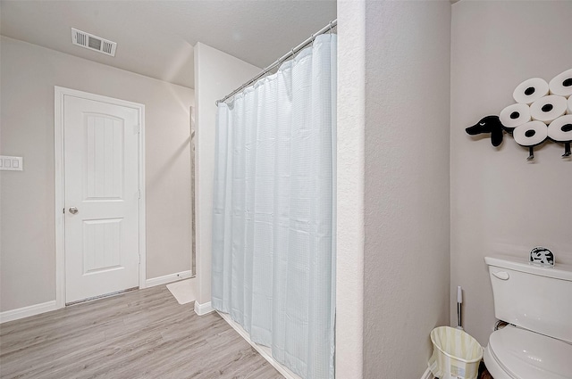 bathroom with toilet, a shower with curtain, and hardwood / wood-style floors