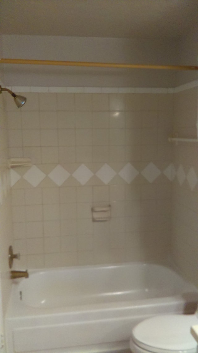 bathroom with tiled shower / bath combo and toilet