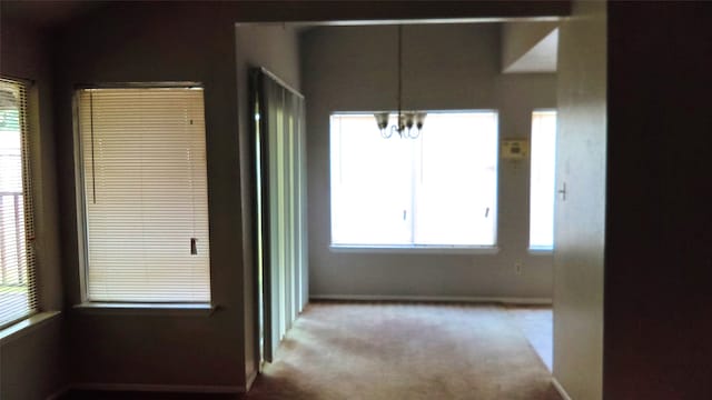 hall featuring an inviting chandelier and light colored carpet