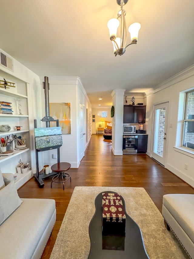 living room with a chandelier, built in shelves, crown molding, and dark wood-type flooring