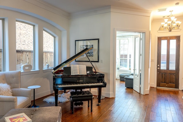 entrance foyer with hardwood / wood-style floors, an inviting chandelier, and ornamental molding