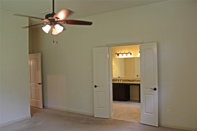 unfurnished bedroom featuring baseboards, ensuite bath, ceiling fan, and light carpet