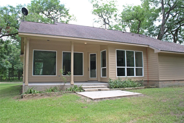 rear view of house with a lawn and roof with shingles