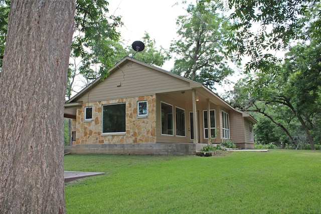 rear view of house featuring a yard and stone siding