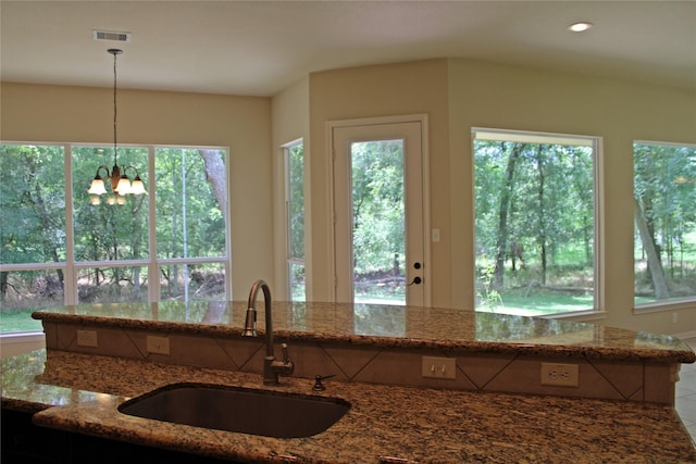 kitchen featuring a sink, pendant lighting, dark stone countertops, and a wealth of natural light