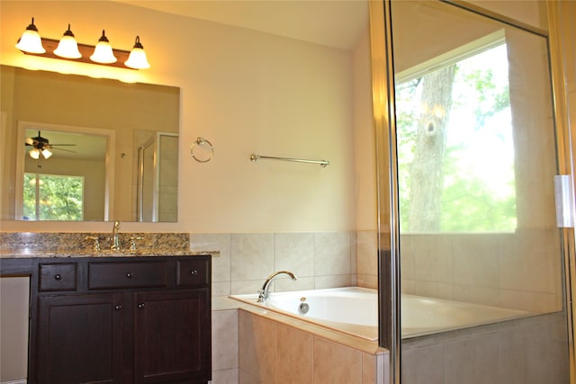 full bath featuring a stall shower, vanity, a healthy amount of sunlight, and a garden tub