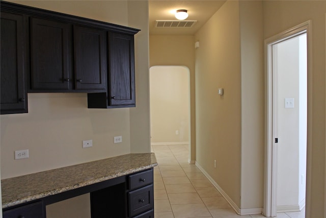 kitchen with baseboards, visible vents, light tile patterned floors, and built in study area