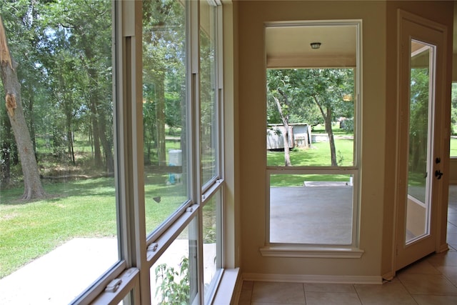 doorway with baseboards, light tile patterned floors, and plenty of natural light