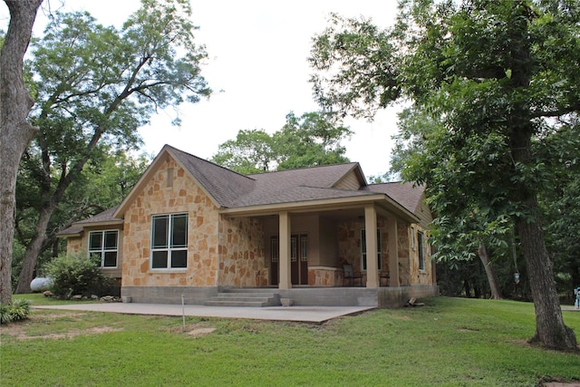 back of property with a patio, a lawn, stone siding, and roof with shingles