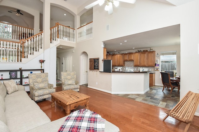 living room featuring a high ceiling, hardwood / wood-style flooring, ceiling fan, and sink