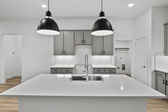 5822 Dawning Sun St, Fulshear, TX 77441 - kitchen with gray cabinetry, a sink, light wood-style flooring, decorative backsplash, and recessed lighting