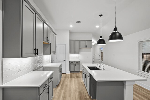 5822 Dawning Sun St, Fulshear, TX 77441 - kitchen with gray cabinetry, a sink, light wood finished floors, decorative backsplash, and recessed lighting
