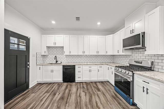 kitchen featuring light stone countertops, hardwood / wood-style floors, white cabinetry, appliances with stainless steel finishes, and sink