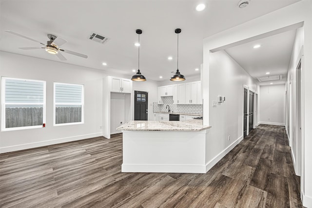 kitchen featuring dark hardwood / wood-style flooring, light stone counters, white cabinetry, decorative light fixtures, and tasteful backsplash