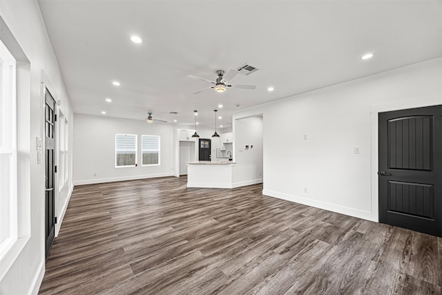 unfurnished living room with dark hardwood / wood-style flooring and ceiling fan