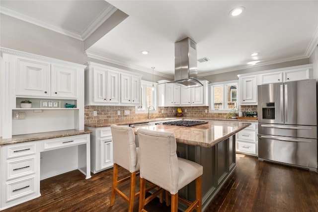 kitchen with white cabinets, a kitchen breakfast bar, light stone countertops, a kitchen island, and stainless steel fridge