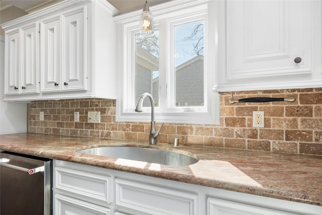 kitchen featuring hanging light fixtures, light stone countertops, white cabinets, stainless steel dishwasher, and sink